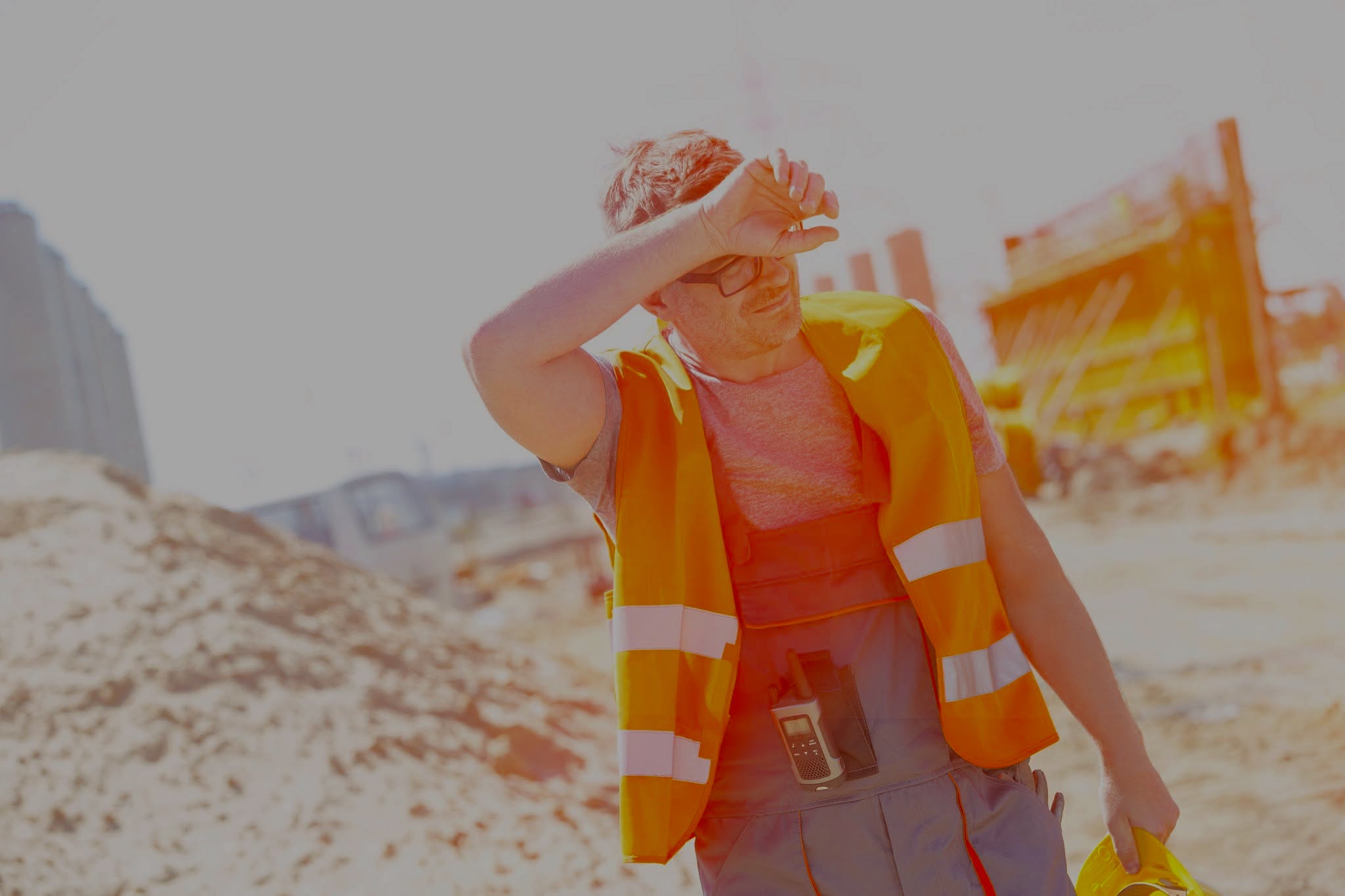 Tired construction worker wiping forehead at site
